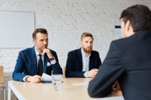La scène montre deux dirigeants face à un clients dans une salle de réunion présentant leur stratégie de tests afin de corriger des anomalies.