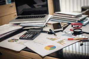 Un ordinateur se trouve sur un bureau derrière une pile de dossiers de test logiciel.